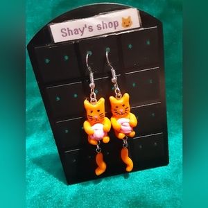 Orange tabby cat playing with yarn earrings